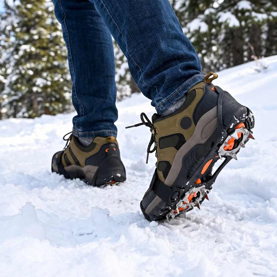 Hiking boots with ice traction crampons walking on snow