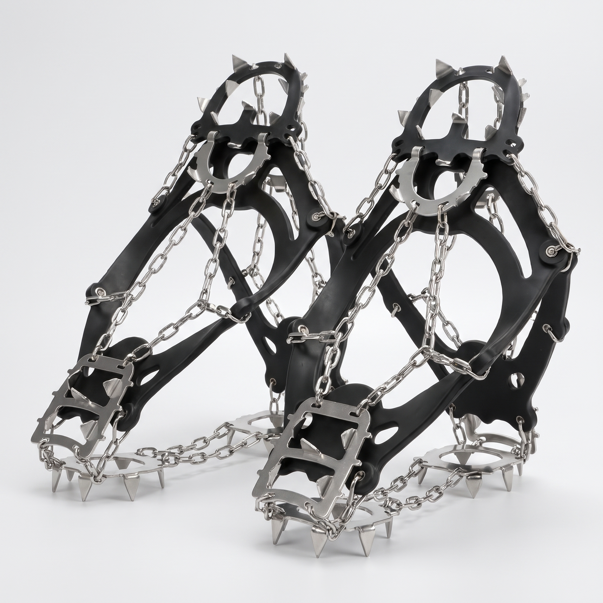 Ice traction cleats with stainless steel chains and metal studs on a plain studio background