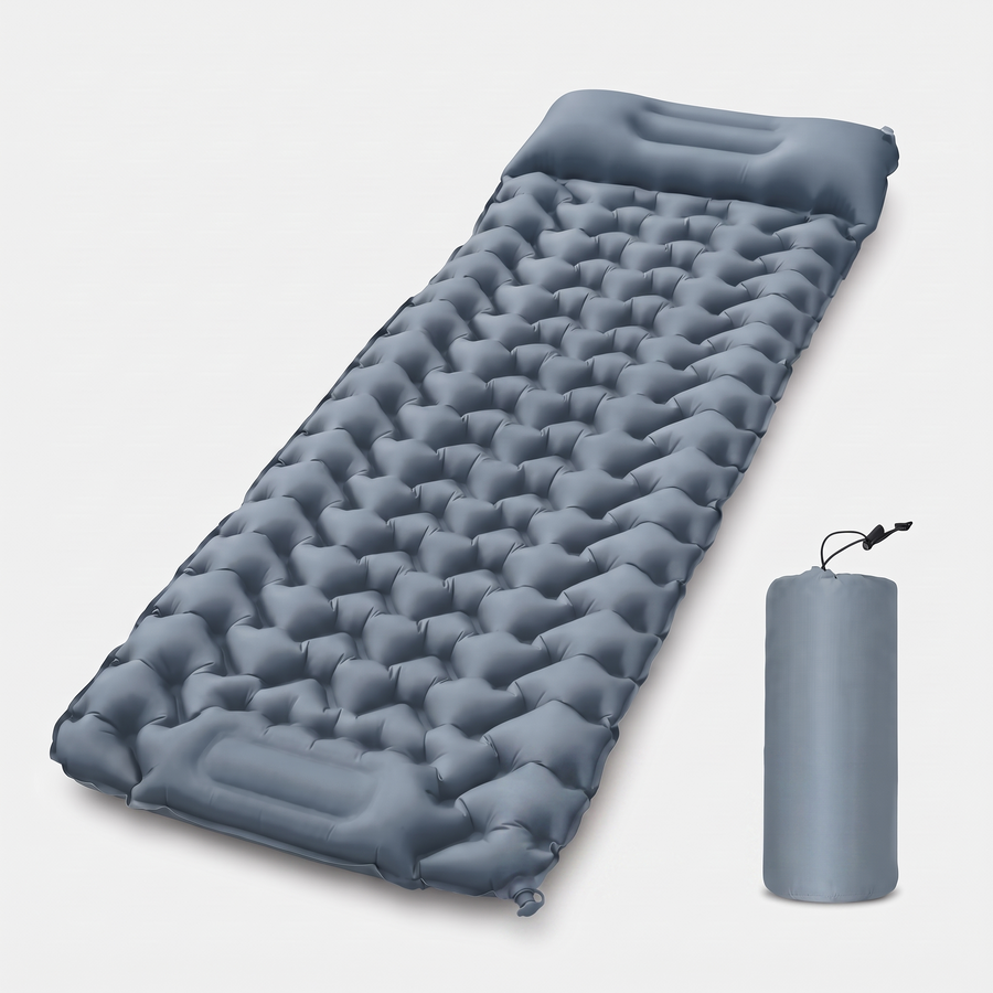 Ultralight inflatable sleeping pad with air cell baffles and built-in pillow beside its stuff sack on a plain studio background